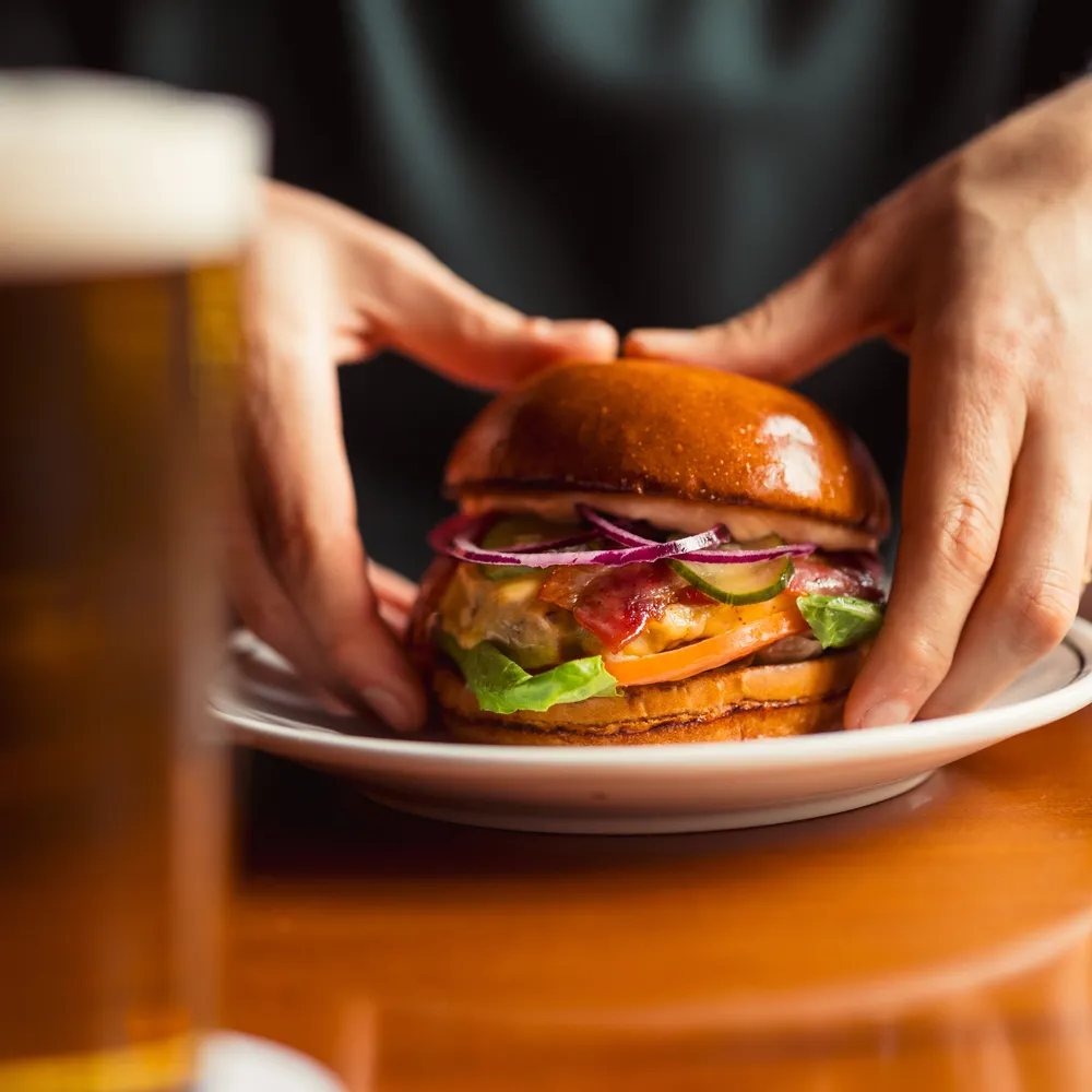 Burger servido à mesa, com um copo de cerveja ao lado